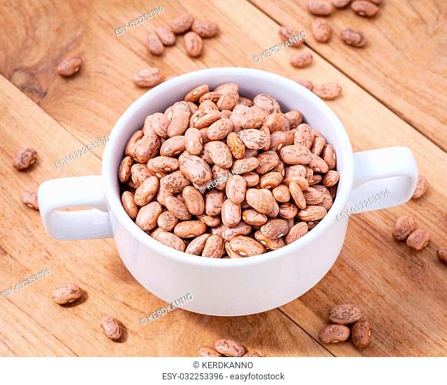 Close up Brown pinto beans in white bowl on wooden background. Selective focus depth of field