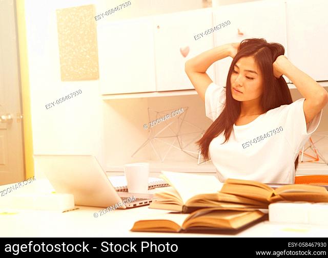 Toned Portrait of tired and exhausted Asian student sitting in front of laptop computer. Beautiful lady feeling to go to bed