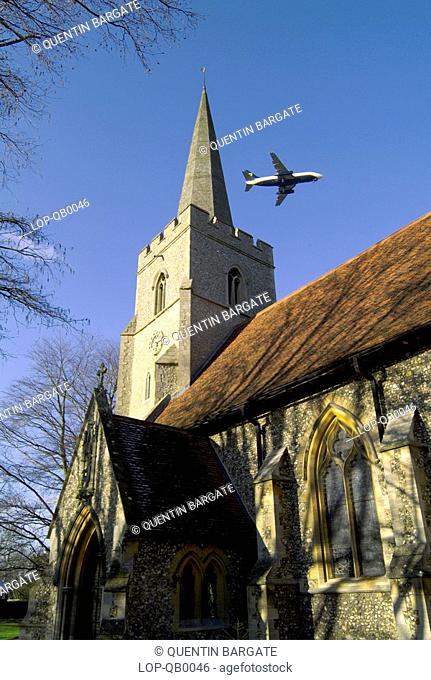 England, Essex, Great Hallingbury, St Giles Church with plane overhead. A Roman camp, hexagonal in shape, double-ditched