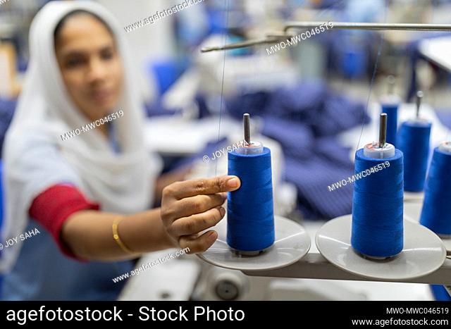 A female worker is taking thread from ribbons for sewing clothes at a readymade garment factory in Gazipur, Bangladesh. The ready-made garment (RMG) industry is...