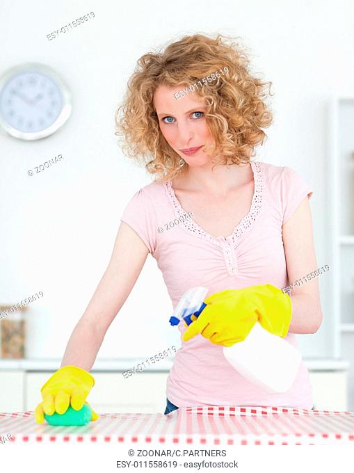Pretty red-haired woman cleaning a cutting board in the kitchen