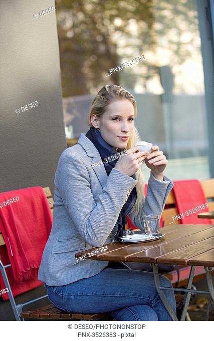 Pensive pretty woman enjoying a cup of coffee in city center