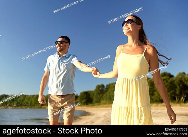 happy couple holding hands on summer beach