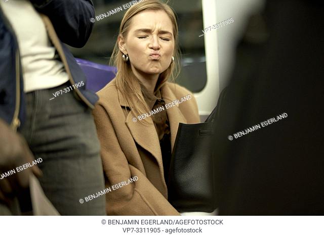 fashionable blogger woman sitting in metro, using public transportation, during fashion week, in city Paris, France