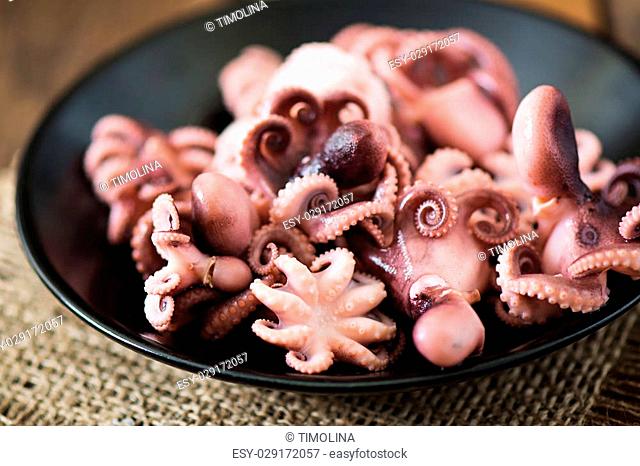 Boiled small octopus on a black plate