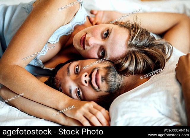 Romantic young couple lying on bed at home