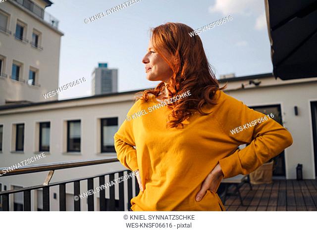 Redheaded woman standing on roof terrace