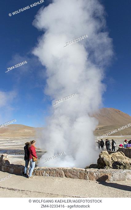 Tourists looking at the steam rising from hot springs at El Tatio Geysers geothermic basin near San Pedro de Atacama in the Atacama Desert, northern Chile