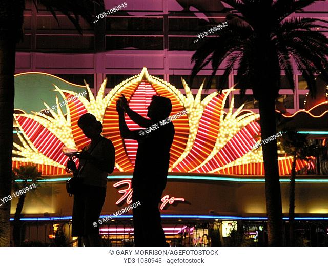 Silhouettes of tourists on the Las Vegas Strip in front of the neon Flamingo Casino sign