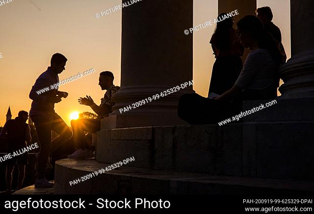 18 September 2020, Bavaria, Munich: Visitors to the English Garden enjoy the evening atmosphere at the ""Monopteros"" as the sun sets
