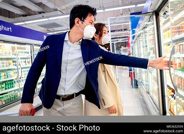 Wearing a mask of the young couple shopping in the supermarket