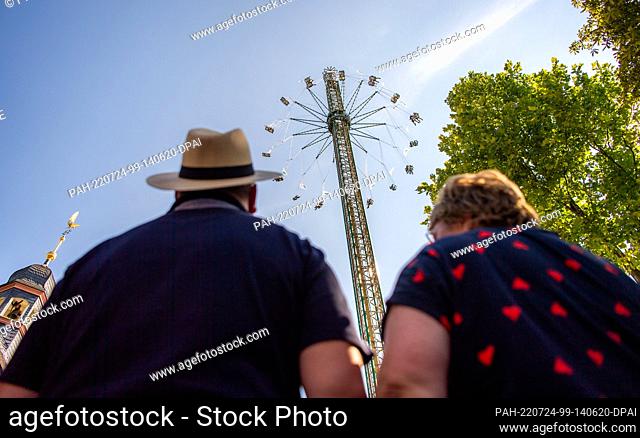 24 July 2022, North Rhine-Westphalia, Paderborn: Two fairgoers look up at the giant chain carousel. Federal President Steinmeier comes to Paderborn as part of...