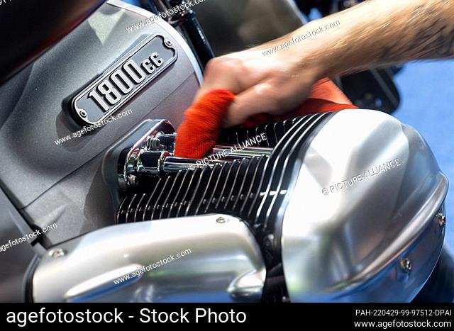 29 April 2022, Thuringia, Erfurt: A man cleans the pushrods of the boxer engine of a BMW R18 motorcycle at the Erfurt Motor Show