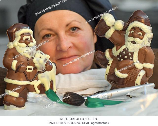 09 October 2018, Brandenburg, Hammelspring: Cornelia Grünberg, employee of Chocolaterie Hammelspring, shows chocolate Santa Clauses