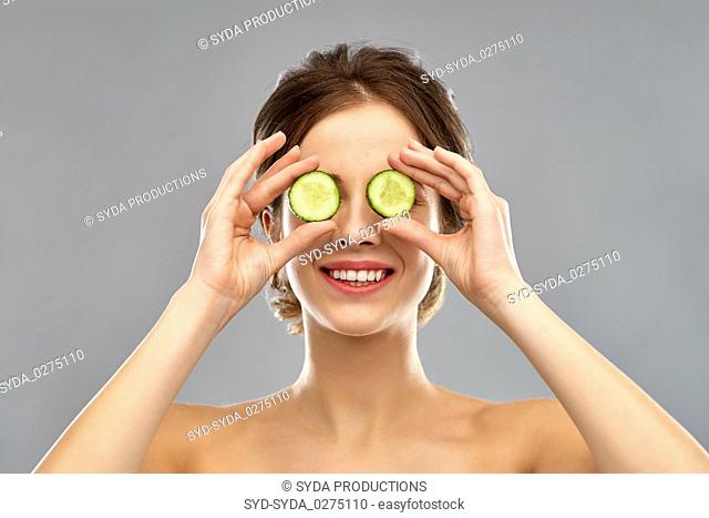 smiling woman with cucumber over grey background