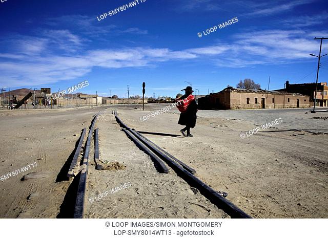 Traditionally dressed lady crossing train tracks in Uyuni