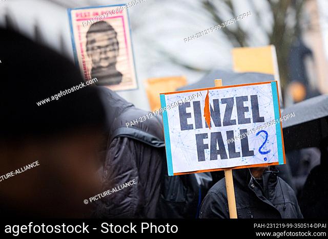PRODUCTION - 19 December 2023, North Rhine-Westphalia, Dortmund: Protesters stand in front of the district court with posters showing the portrait of...