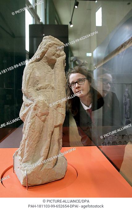 03 November 2018, Saxony-Anhalt, Magdeburg: A woman looks at a sandstone figure in the new cathedral museum Ottonianum. The museum informs about Emperor Otto...