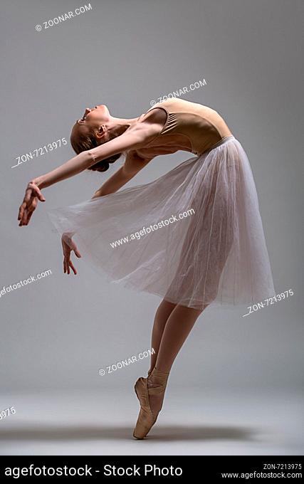 Graceful ballerina standing on toes bending the back. Studio shot
