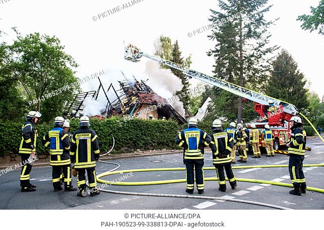 23 May 2019, Schleswig-Holstein, Wohltorf: Firefighters are standing in front of the ruins of a house that was destroyed in a fire