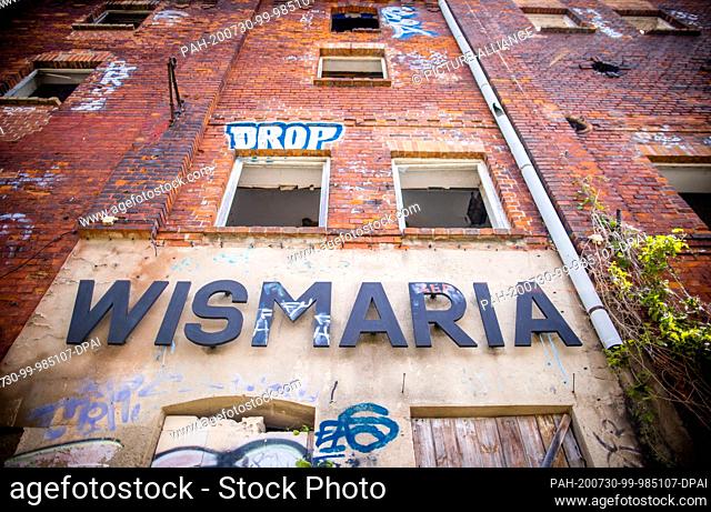 28 July 2020, Mecklenburg-Western Pomerania, Wismar: The 130 year old empty and partially collapsed malt factory stands on the Mühlenteich pond right next to...