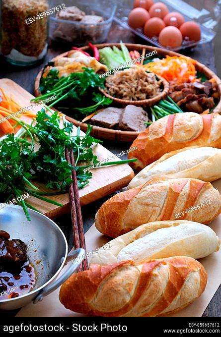 Famous Vietnamese food is banh mi thit, popular street food from bread stuffed with raw material: pork, ham, pate, egg and fresh herbs as scallions, coriander