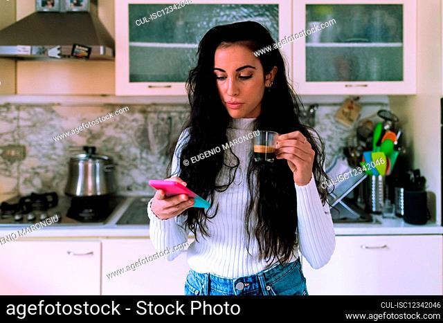 Young woman having coffee and looking at her phone