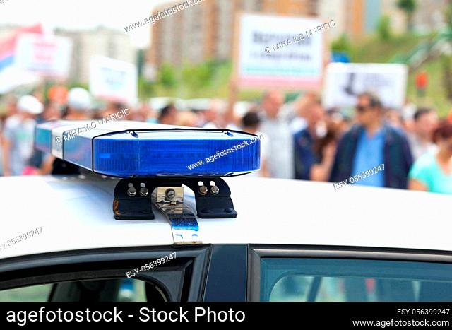 Police car flashing lights in focus with crowd out of focus in the background