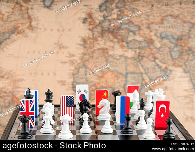 Country flag symbols on the chessboard with figures on the background of the political map of the world. Conceptual photo of a political game