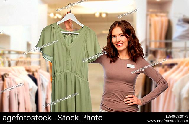 happy female shop assistant with dress on hanger