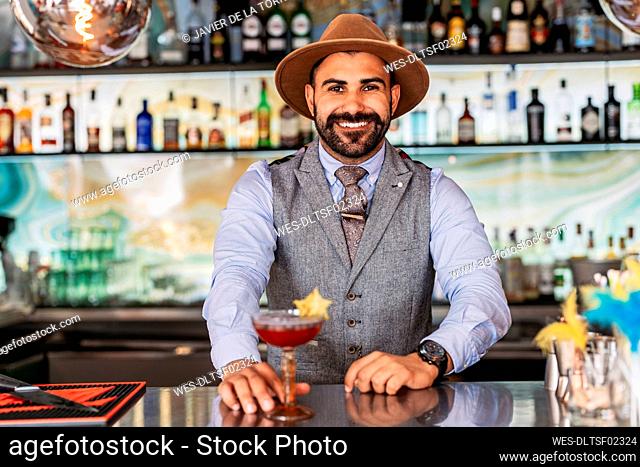 Smiling male bartender serving cocktail in bar