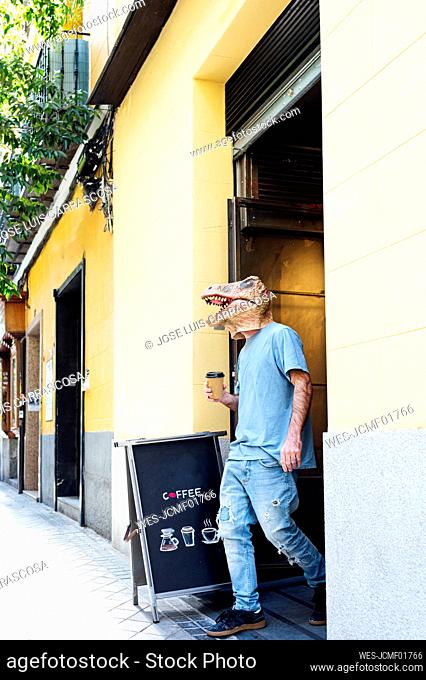 Man wearing dinosaur mask with coffee leaving from coffee shop