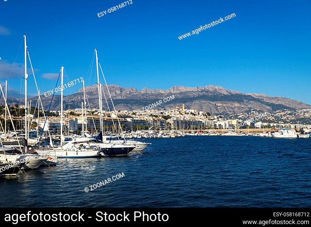 Yachts at the port of Altea with view on mountain range with old city and cathedral on cloudless sunny day, Altea, Costa Blanca, Spain