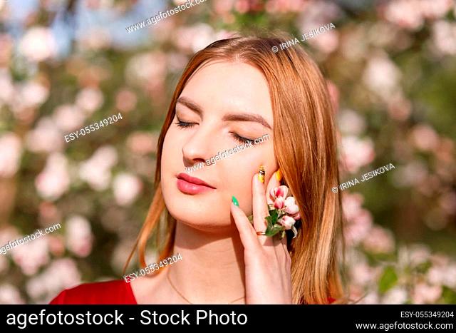 Young girl with her hair in a blooming apple orchard, ecology, care