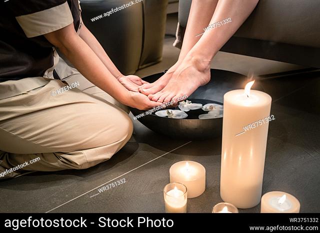 Close-up of the hands of an Asian therapist during foot washing treatment in spa and beauty center