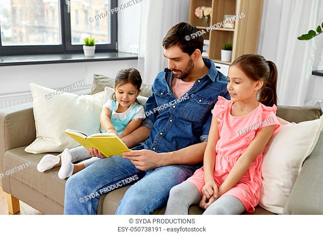 happy father with daughters reading book at home