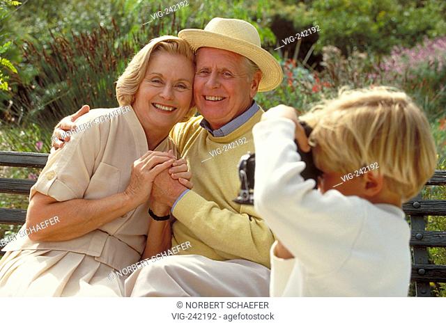 outdoor, park-scene, 6-year-old blond boy makes a photo of his grandparents sitting on a park bench  - GERMANY, 19/09/2004
