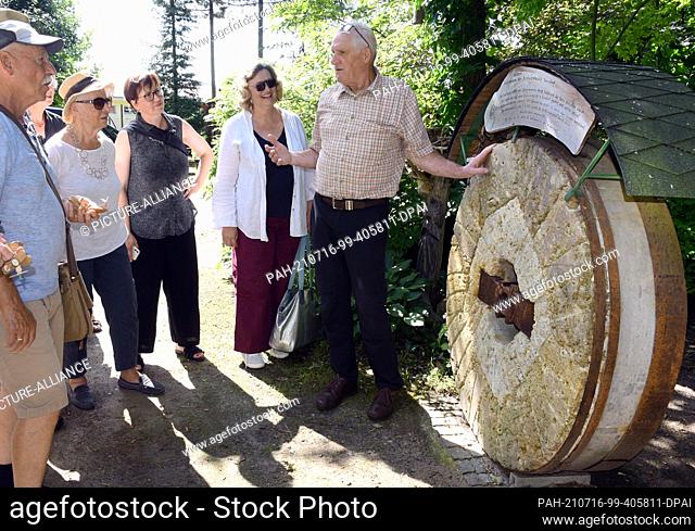 13 July 2021, Saxony-Anhalt, Holzdorf-Jessen: Forester and forest educator Detlef Schulze (r) explains an old millstone from a windmill to a group of visitors...