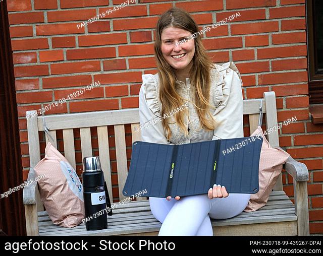 PRODUCTION - 10 July 2023, Bremen: Sarah Winkelmann, an expedition adventurer from Bremen, Germany, sits in her backyard next to her thermos and holds a solar...