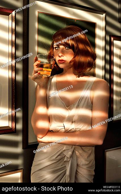 Woman having a drink in a shadowed room