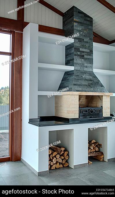 Light room with brick fireplace with gray brick chimney in the white niche. Fireplace is on the dark tabletop. Under fireplace there are two niches with the...