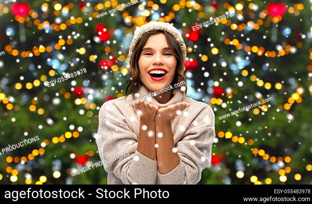 happy woman over christmas tree lights and snow