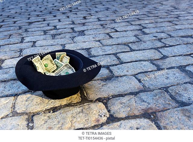 Money in hat on cobblestone street