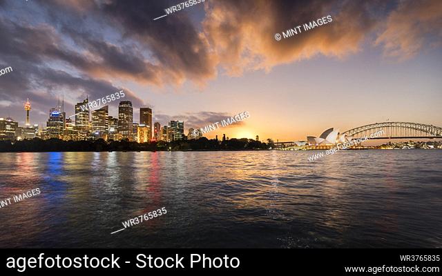 Sydney lit up at dawn seen from the water, including the Sydney Opera House