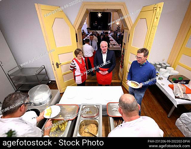 06 December 2023, Thuringia, Erfurt: Andreas Bausewein (center, SPD), Lord Mayor of Erfurt, and helpers serve a hot meal in the Restaurant des Herzens of the...
