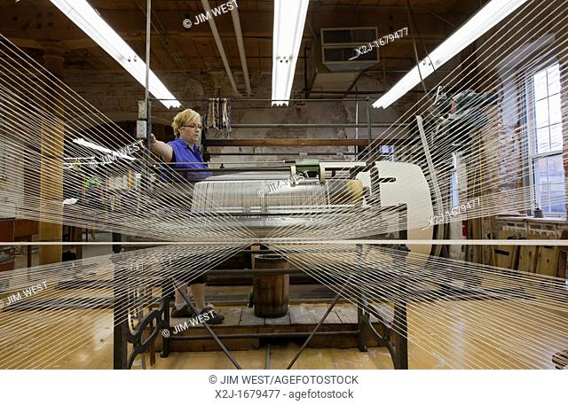 Amana, Iowa - A worker runs a warping creel at the Amana Woolen Mill  The machine gathers up to 240 strands of yarn that will later be woven into cloth on a...