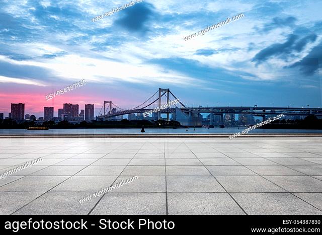 empty pedestrians sidewalk with modern suspension bridge in tokyo against cloud sky at twilight