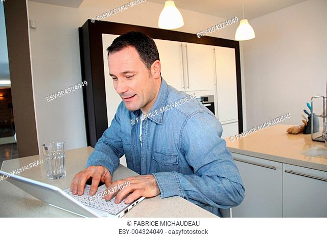 Man using laptop computer in kitchen