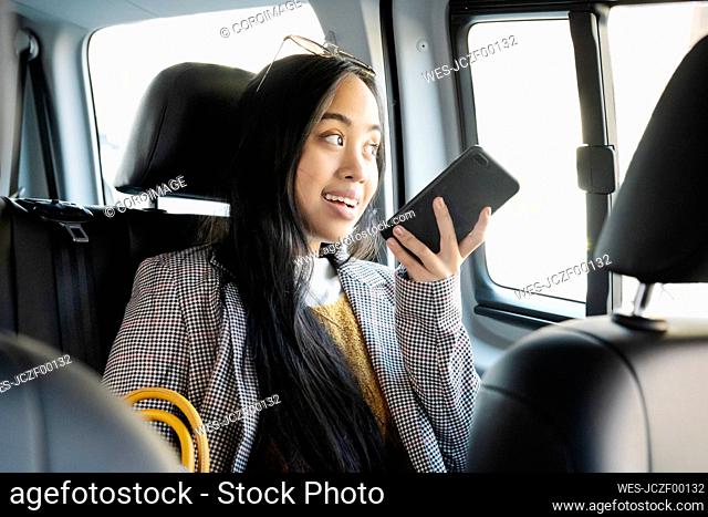 Woman talking over smart phone while sitting in taxi