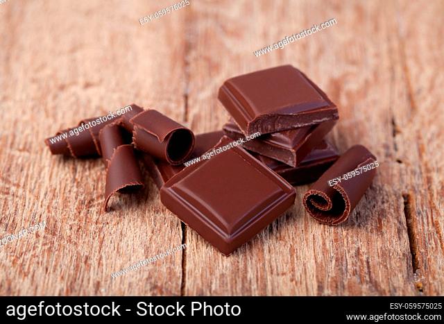Pieces of natural dark chocolate on wooden table